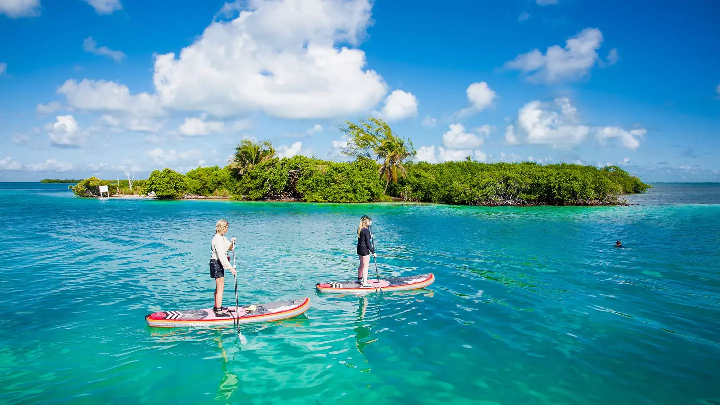 People paddleboard in the waters by Caye Caulker island.