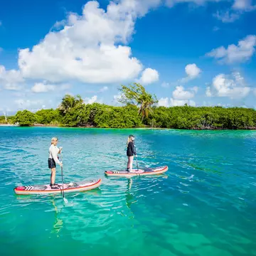 People paddleboard in the waters by Caye Caulker island.