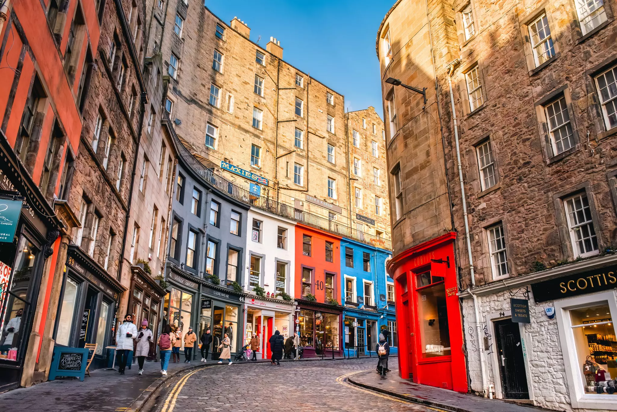 Colorful shopfronts in Edinburgh's Old Town on a bright spring day.