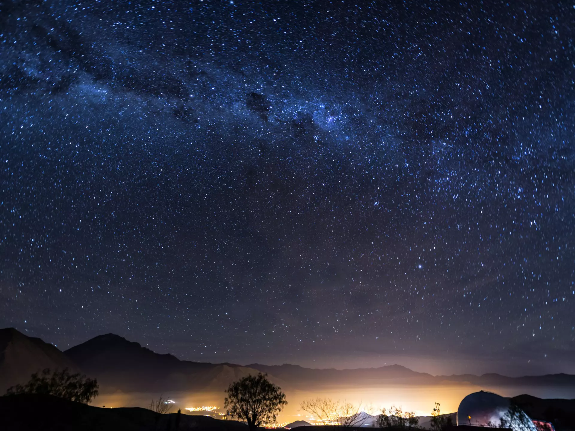 A long-exposure photo of the Milky Way over the lights of the Elqui Valley in Chile.