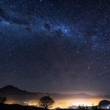 A long-exposure photo of the Milky Way over the lights of the Elqui Valley in Chile.