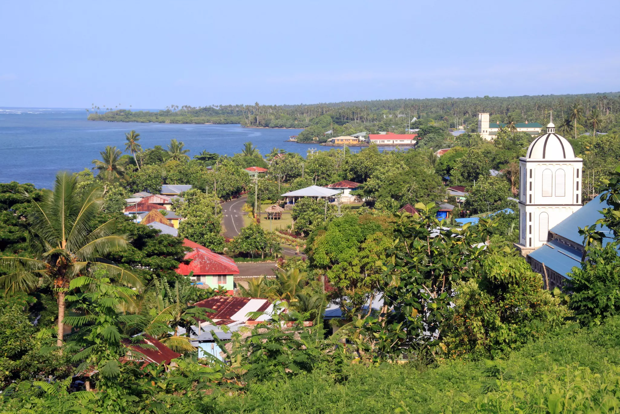 A small coastal settlement surrounded by green foliage and palm trees.