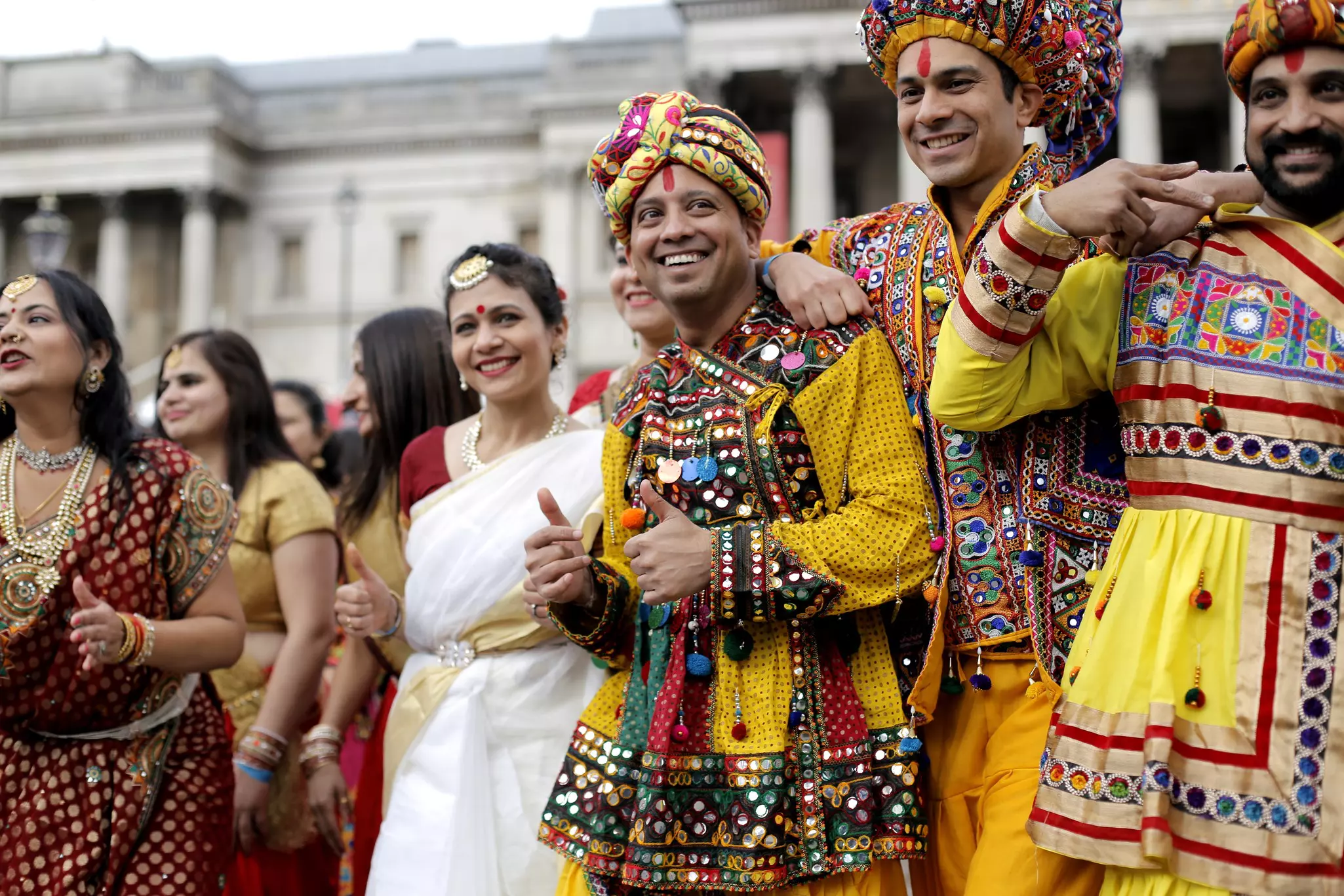 People in elaborate costumes stand closely together at a city square.