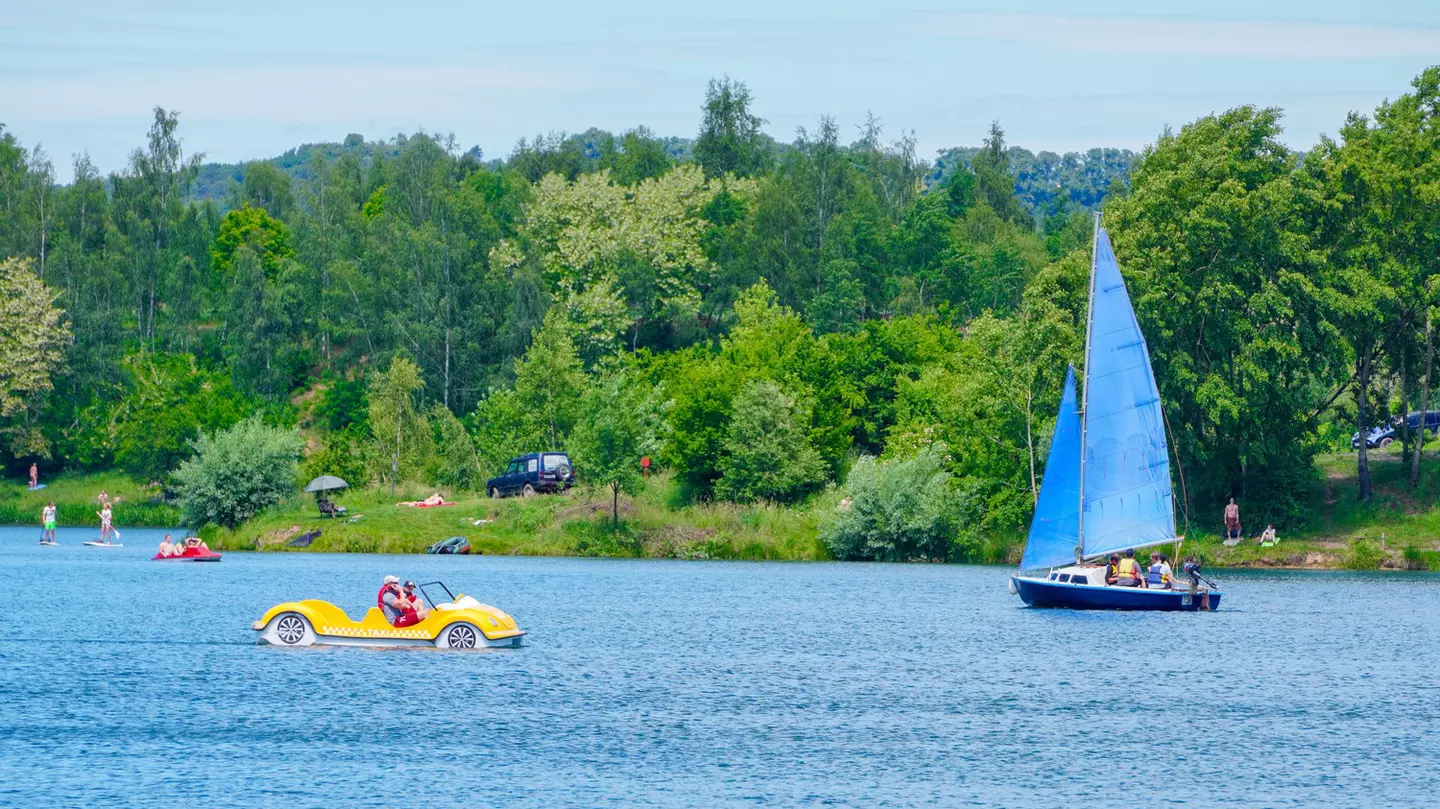 A small sail boat and a peddle boat on a lake on a summer's day