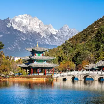 Pagoda and arched marble bridge on Black Dragon Pool in Lijiang with snowy Jade Dragon Snow Mountain behind