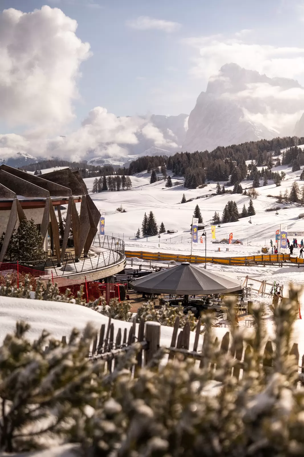 A hotel terrace gives way to ski slopes where a few people are gliding along: COMO Hotels & Resorts, the Dolomites, Italy