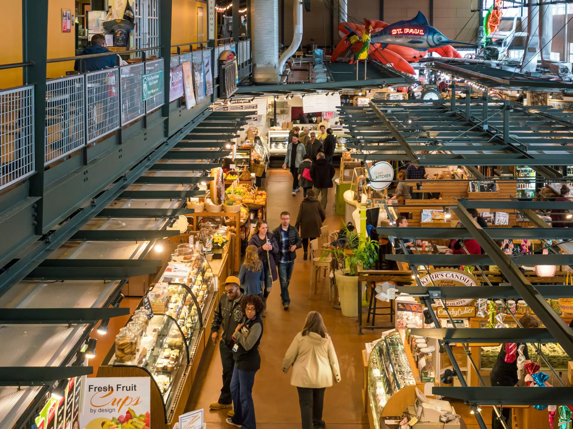 An overhead shot of people walking past stalls in an enclosed public market.