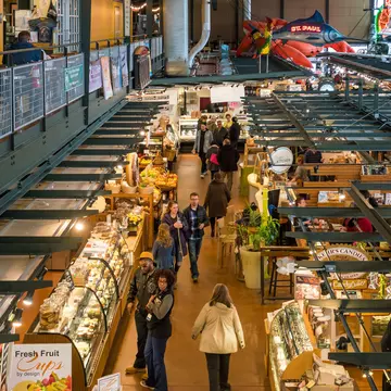 An overhead shot of people walking past stalls in an enclosed public market.