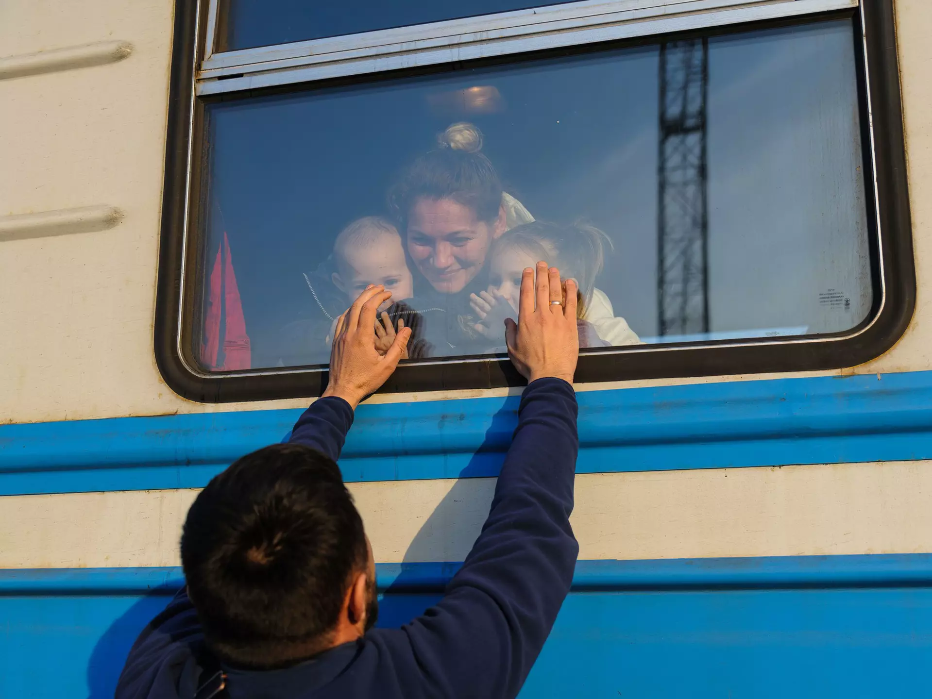 A man gestures to his family outside a train to Poland at