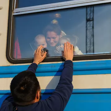 A man gestures to his family outside a train to Poland at