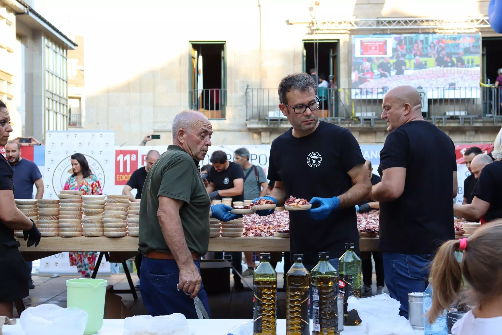 Market sellers prepare plates of fresh octopus at an outdoor seafood festival