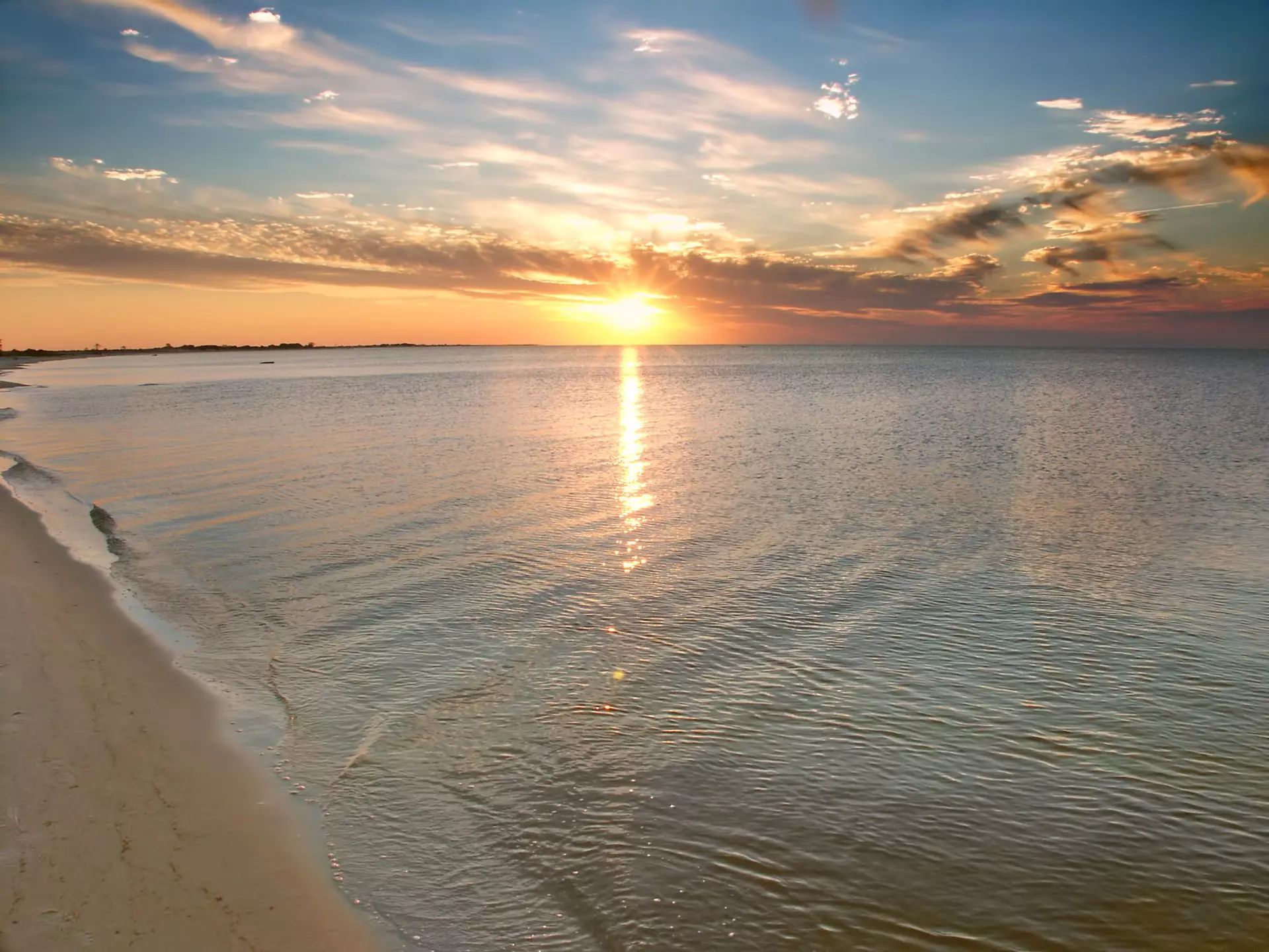 A wide shot of the sun setting over the beach of a barrier island.