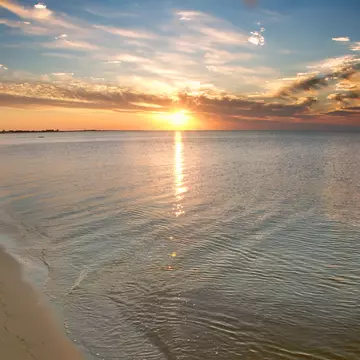 A wide shot of the sun setting over the beach of a barrier island.
