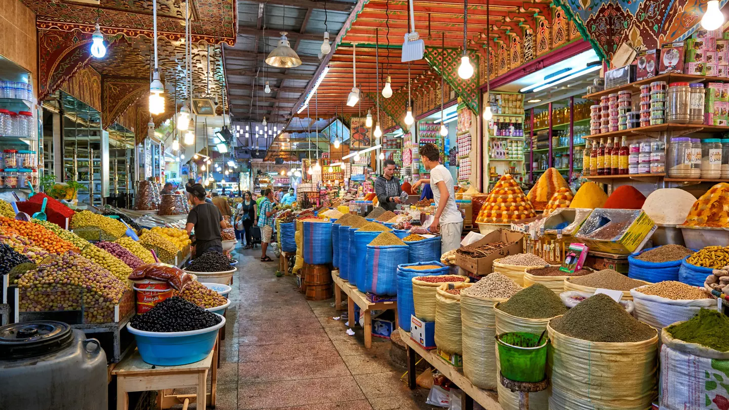 A walkway through stalls selling food and spices at a souq in Morocco.