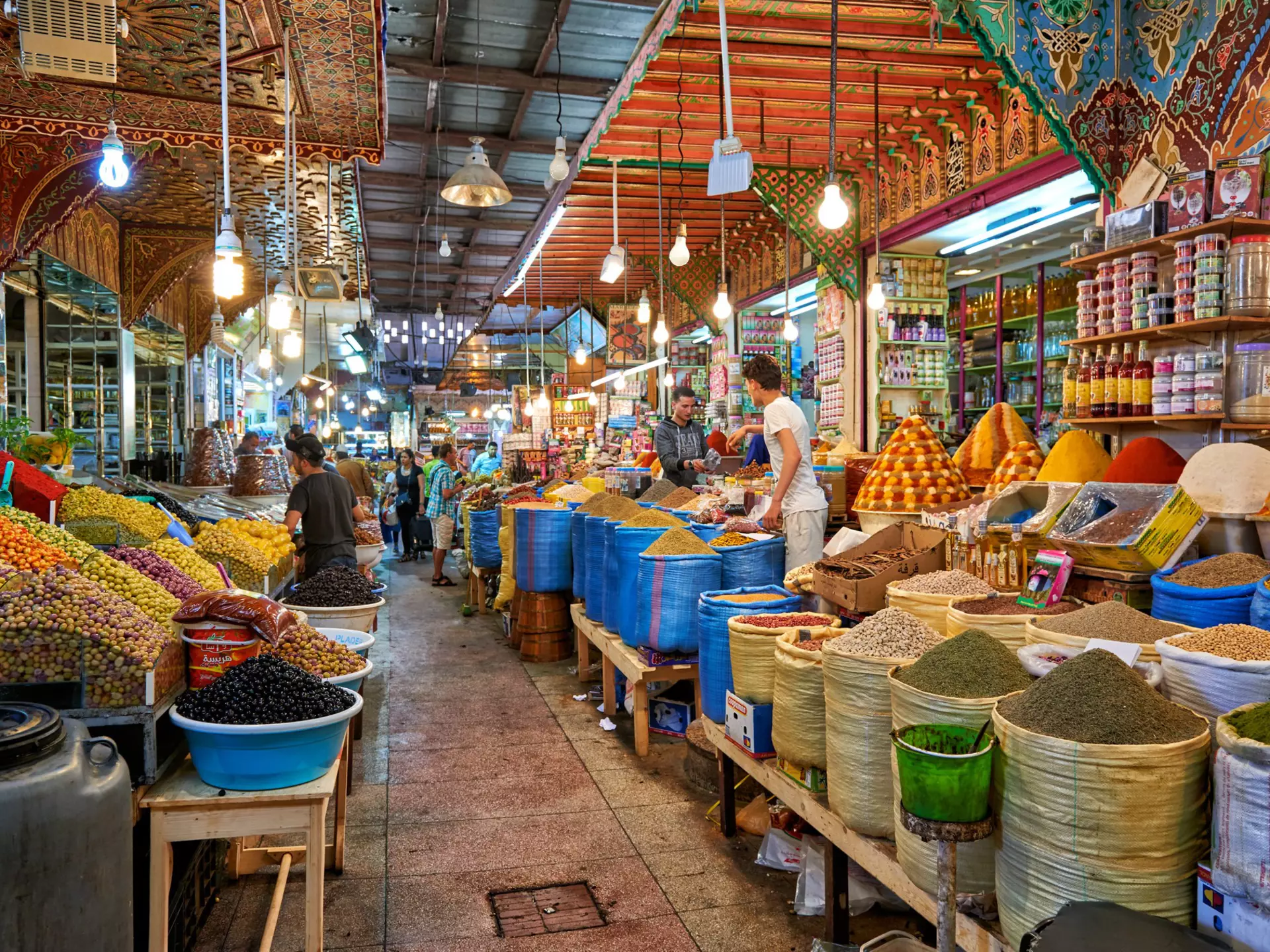 A walkway through stalls selling food and spices at a souq in Morocco.
