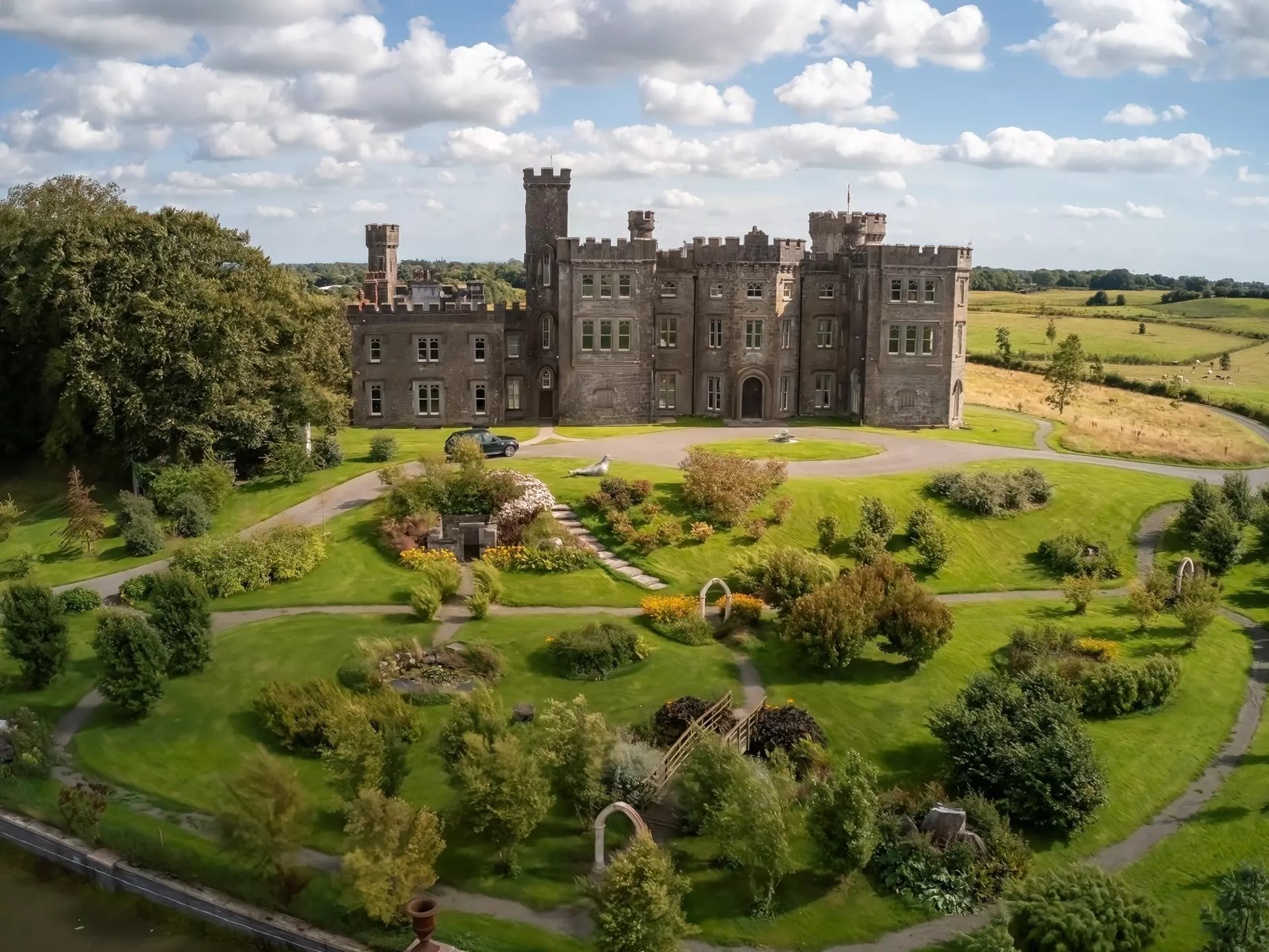 Beautifully restored Killau Castle surrounded by a scenic garden on a sunny day.