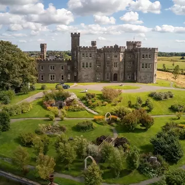 Beautifully restored Killau Castle surrounded by a scenic garden on a sunny day.