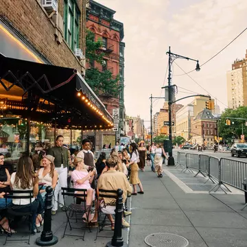 People sitting and chatting in outdoor dining on a New York City street.