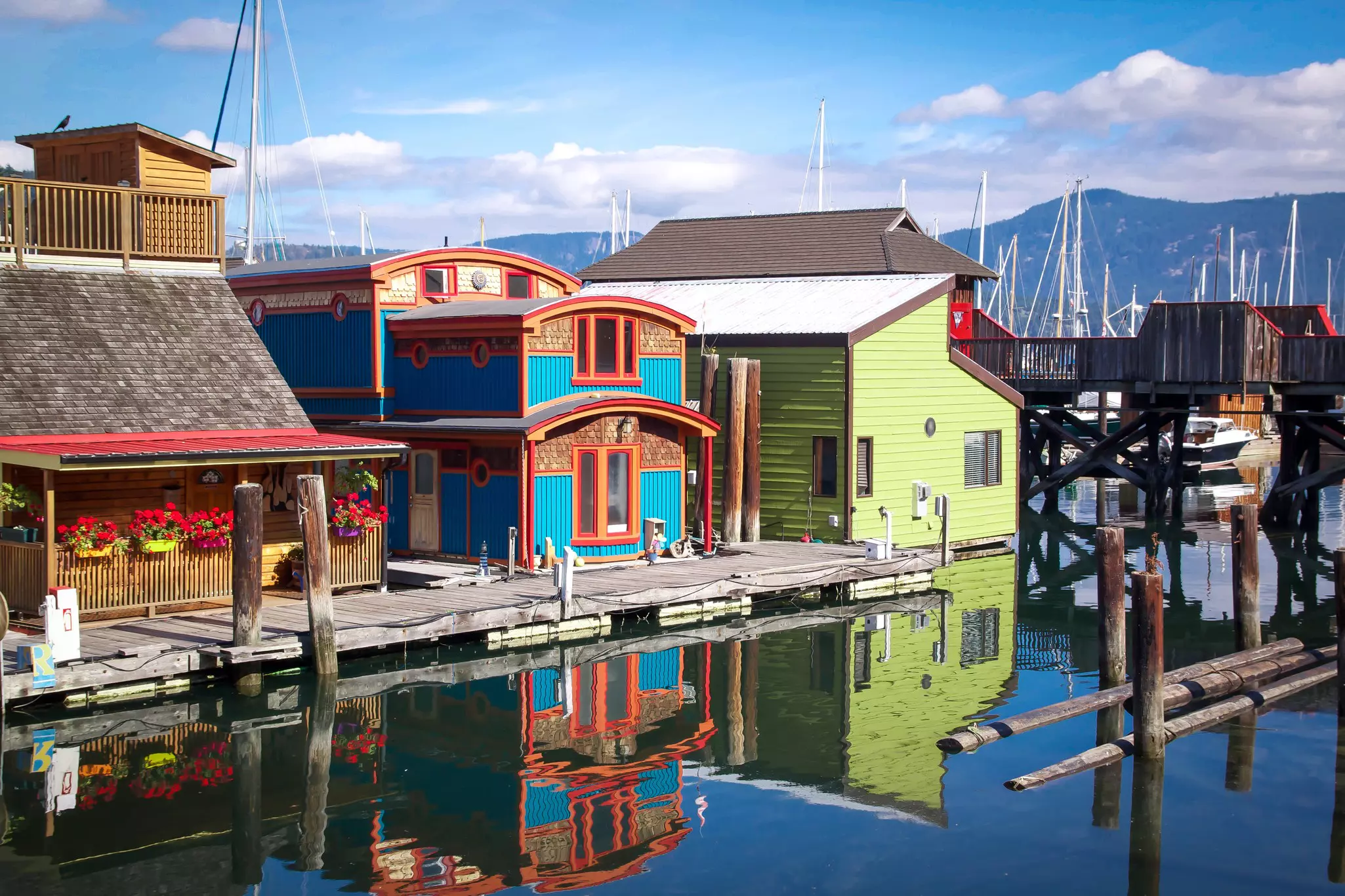 Colorful floating houses and their reflection in a bay on a sunny day.