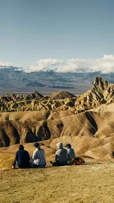Four people sitting in a landscape of dry rock formations.