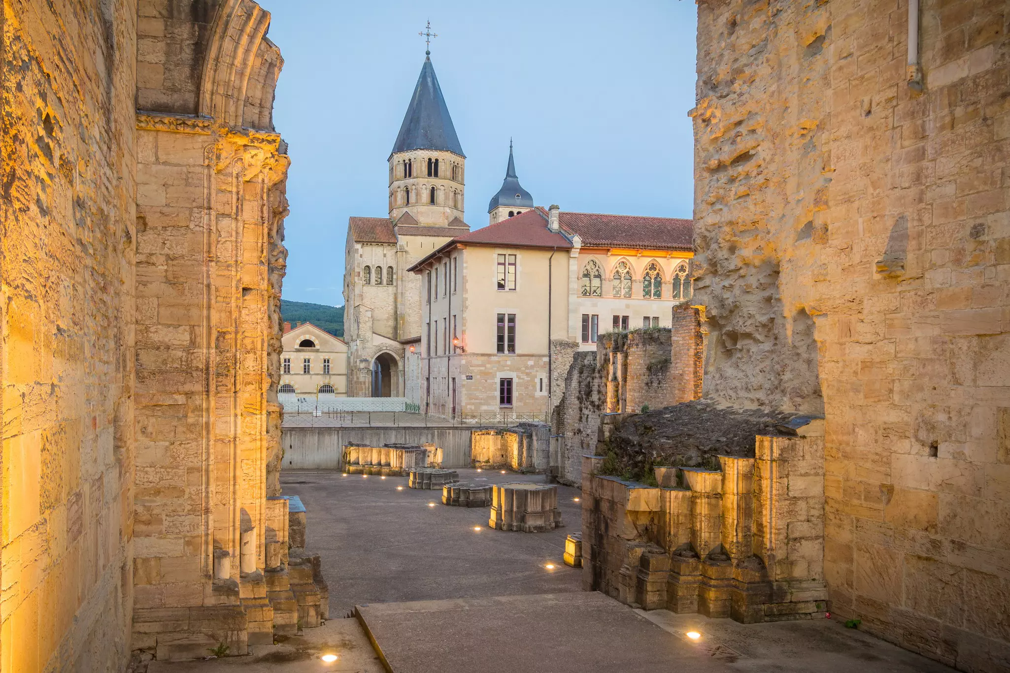 View of historic buildings through a ruined medieval church at dusk.