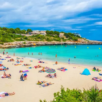 People sun bathing and swimming at Cala Marcal beach