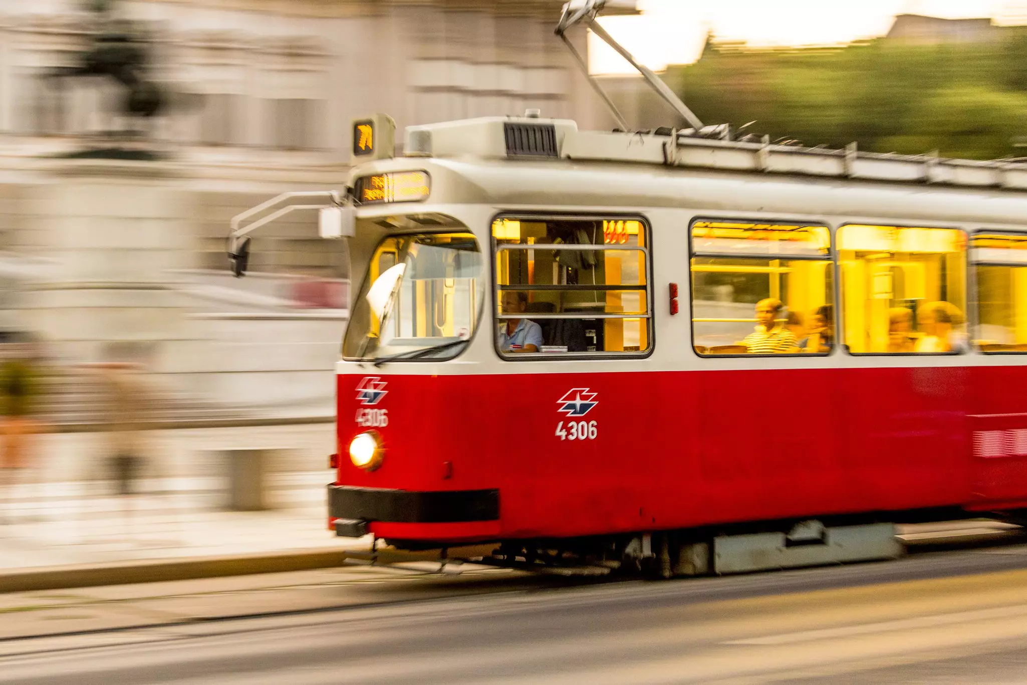 A red tram speeding through a city