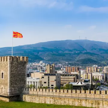 A large fortress tower flying the flag of Macedonia with a city backdrop