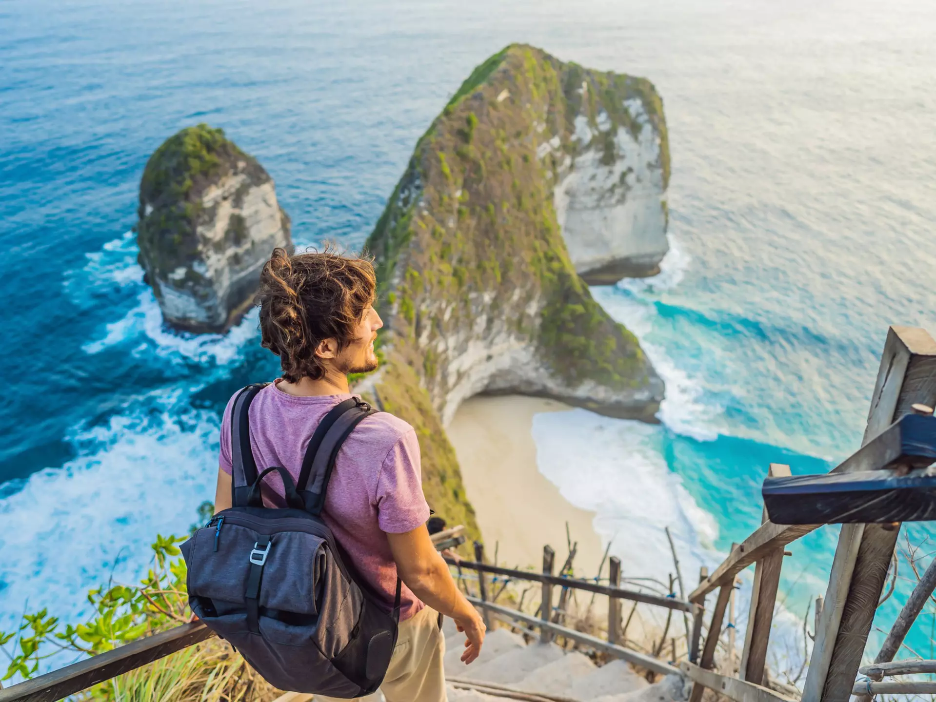 Man stand at viewpoint overlooking at beautiful Kelingking Beach on Nusa Penida Island Bali