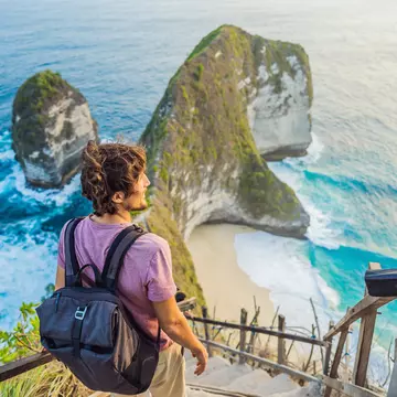 Man stand at viewpoint overlooking at beautiful Kelingking Beach on Nusa Penida Island Bali