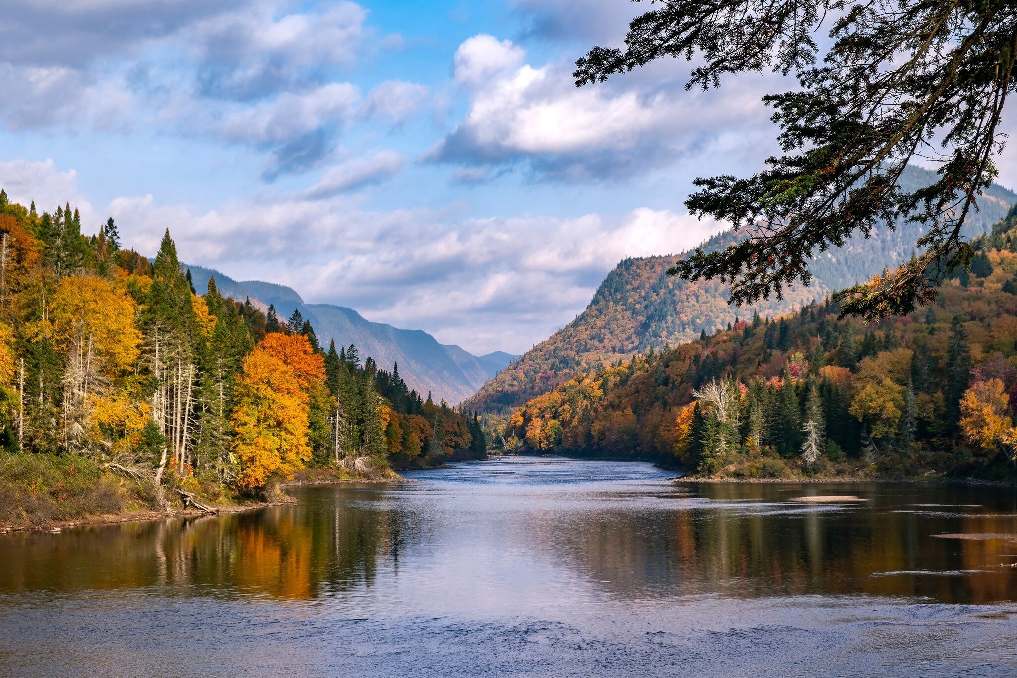 View of autumnal foliage in the mountains and a river in Parc National de la Jacques-Cartier, Canada.