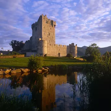 Ross Castle in Killarney next to the river and surrounded by lush green grass