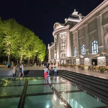 People walking next to the Latvian National Museum of Art on a summer evening in Riga.