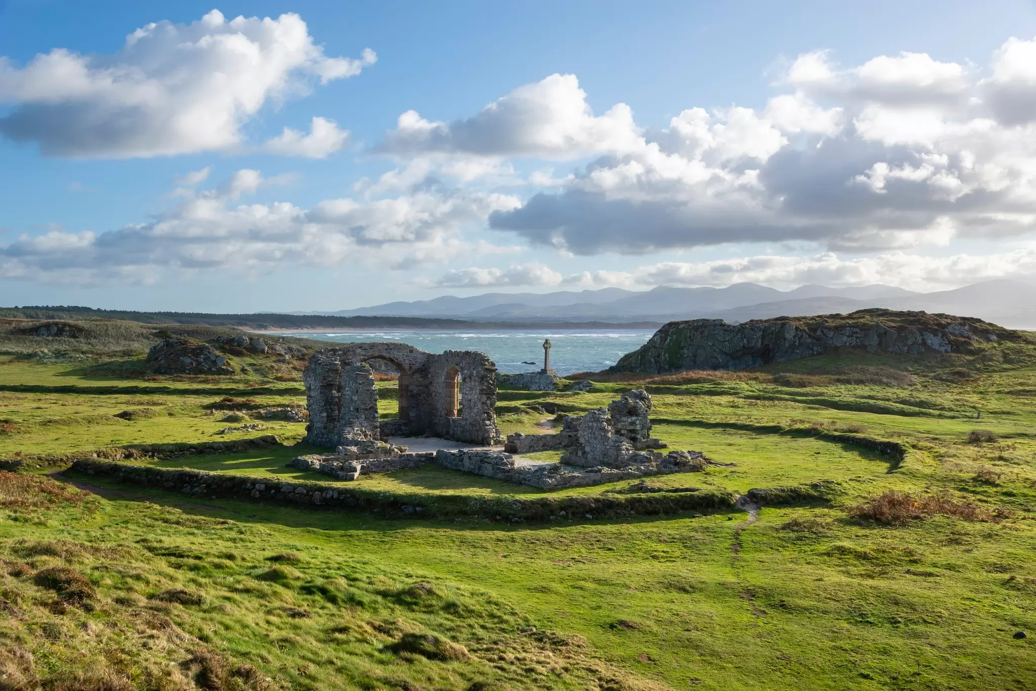 Ruins of a stone structure in a grassy area by the sea.