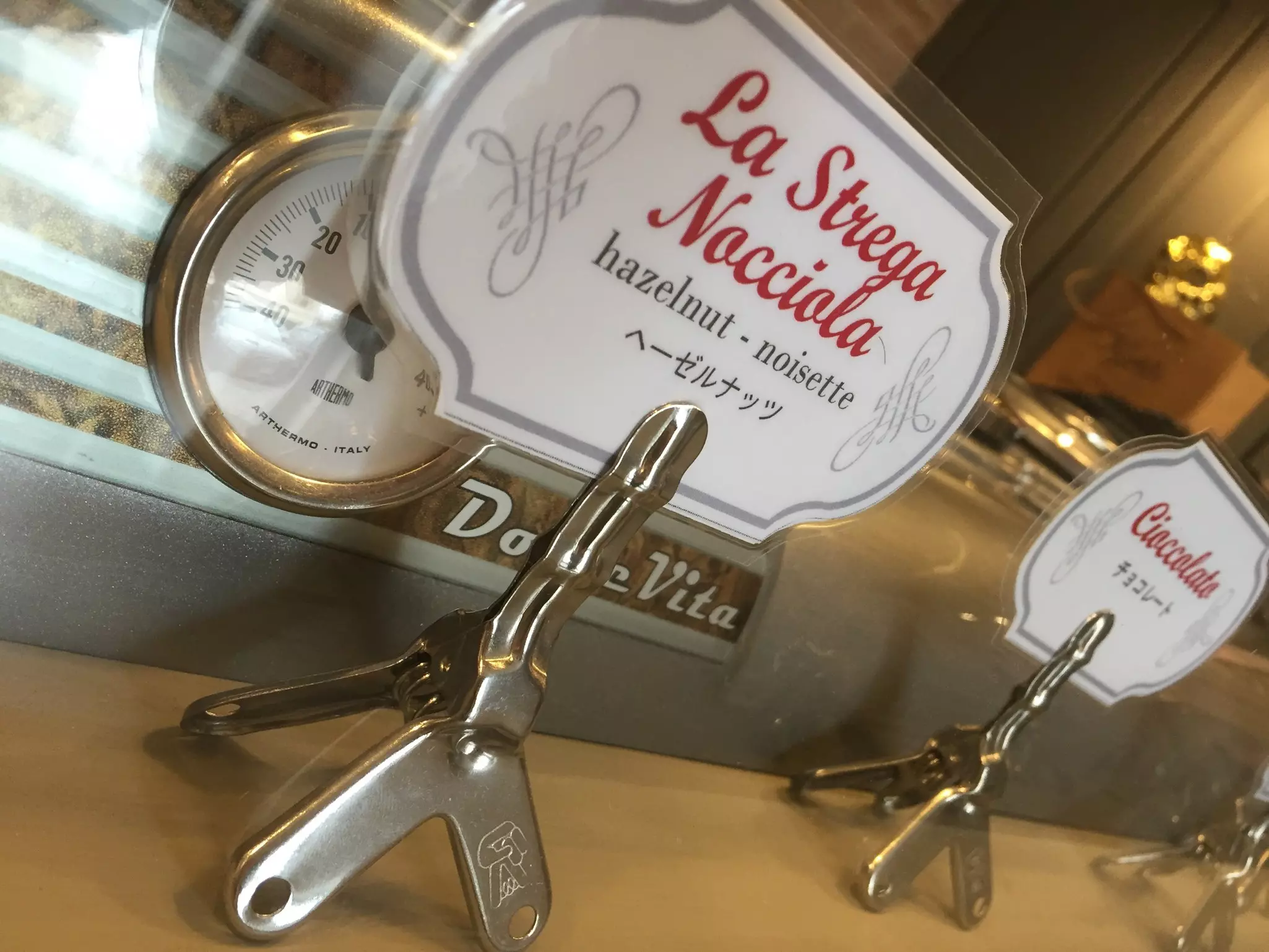 Labels in front of a gelato freezer at La Strega Nocciola Gelateria Artigianale