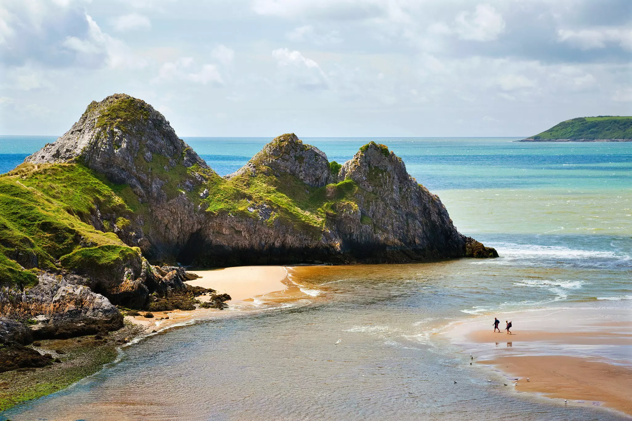 Three rocky peaks at the edge of a sandy bay.