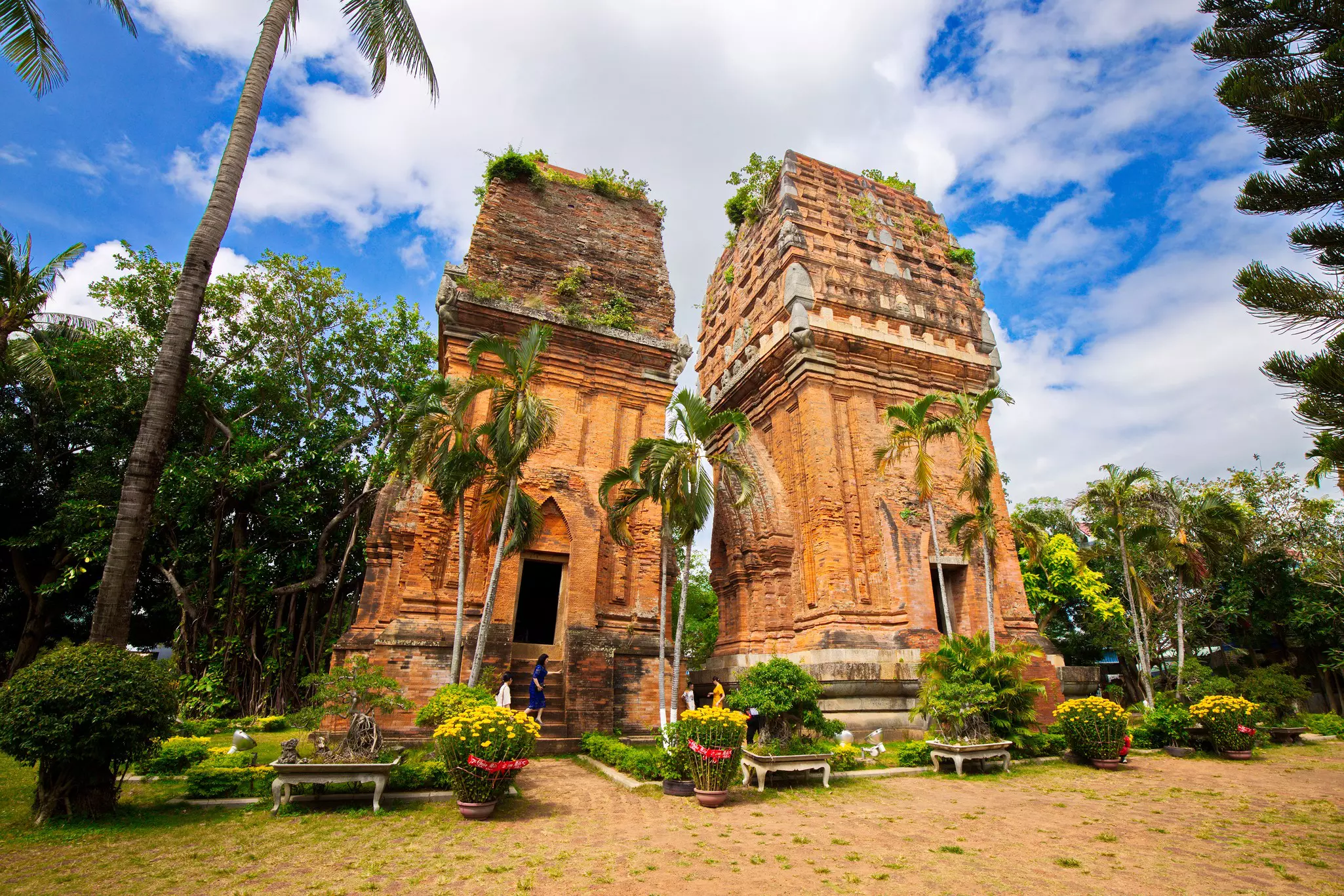 Two ancient red-brick towers stand in a lush garden.
