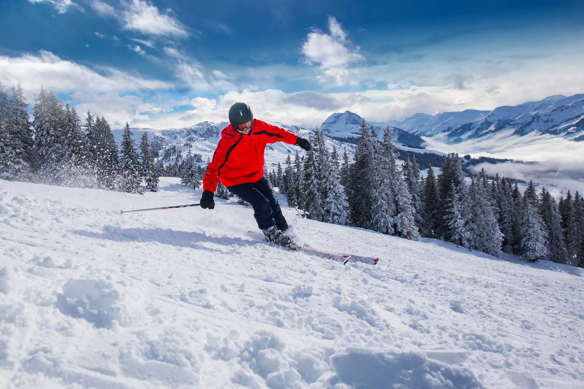 Young happy man skiing in Kitzbuehel ski resort and enjouing the beautiful weather with blue sky and Alpine mountains in Austria.