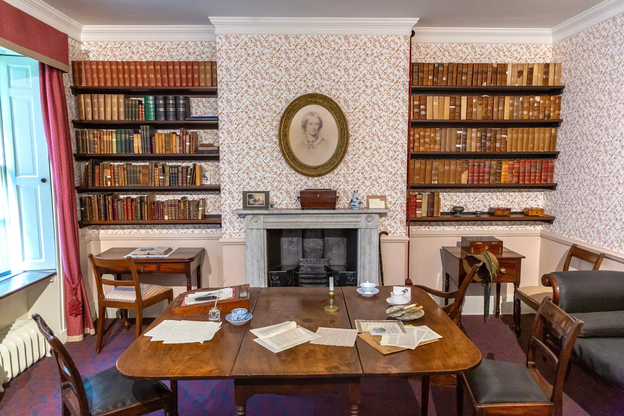 The dining room of a historic home is preserved, with paper and writing implements on the table, Brontë Parsonage Museum, Haworth, West Yorkshire, England