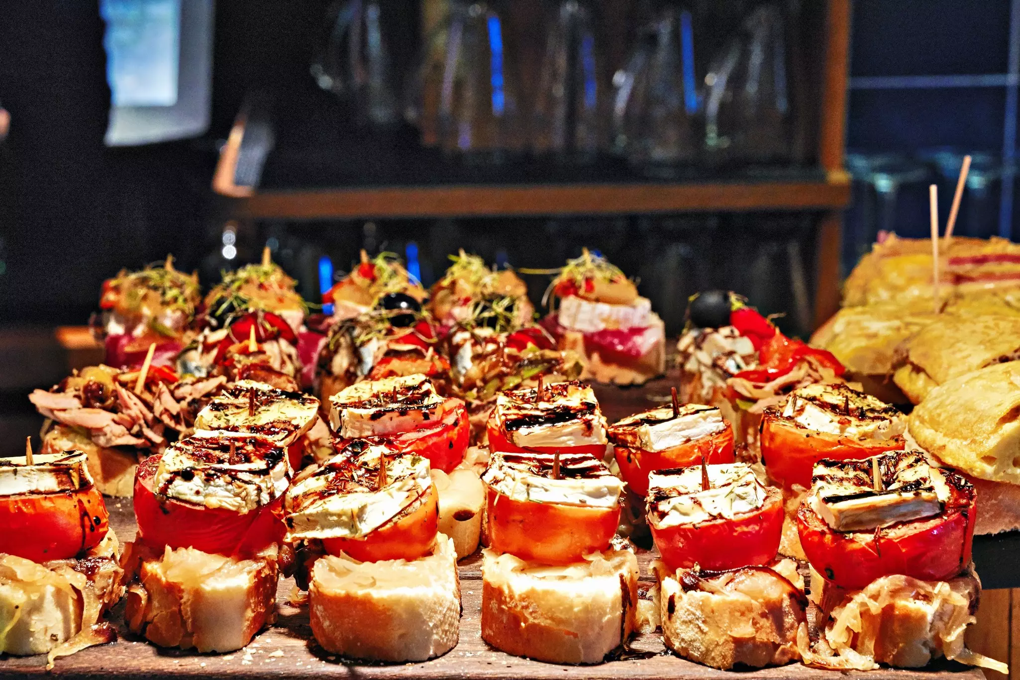 An array of small bar bites are on display on the counter of a restaurant.
