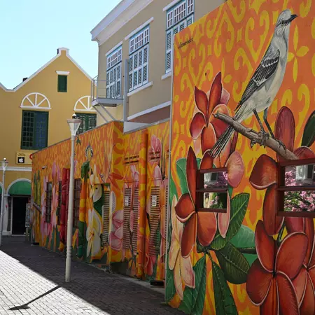 A colorful floral mural on the side of a low building.