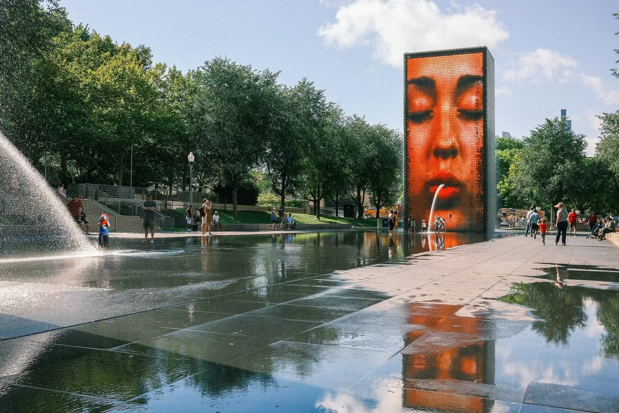 A modern pop art-style fountain in a park where the water appears to coming out of a woman's mouth. 