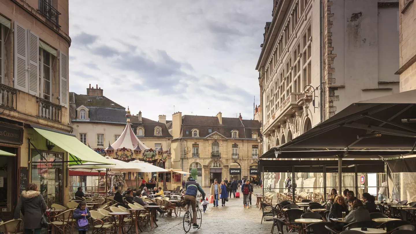 A cobbled street line with cafe tables with people socialising in Dijon, France