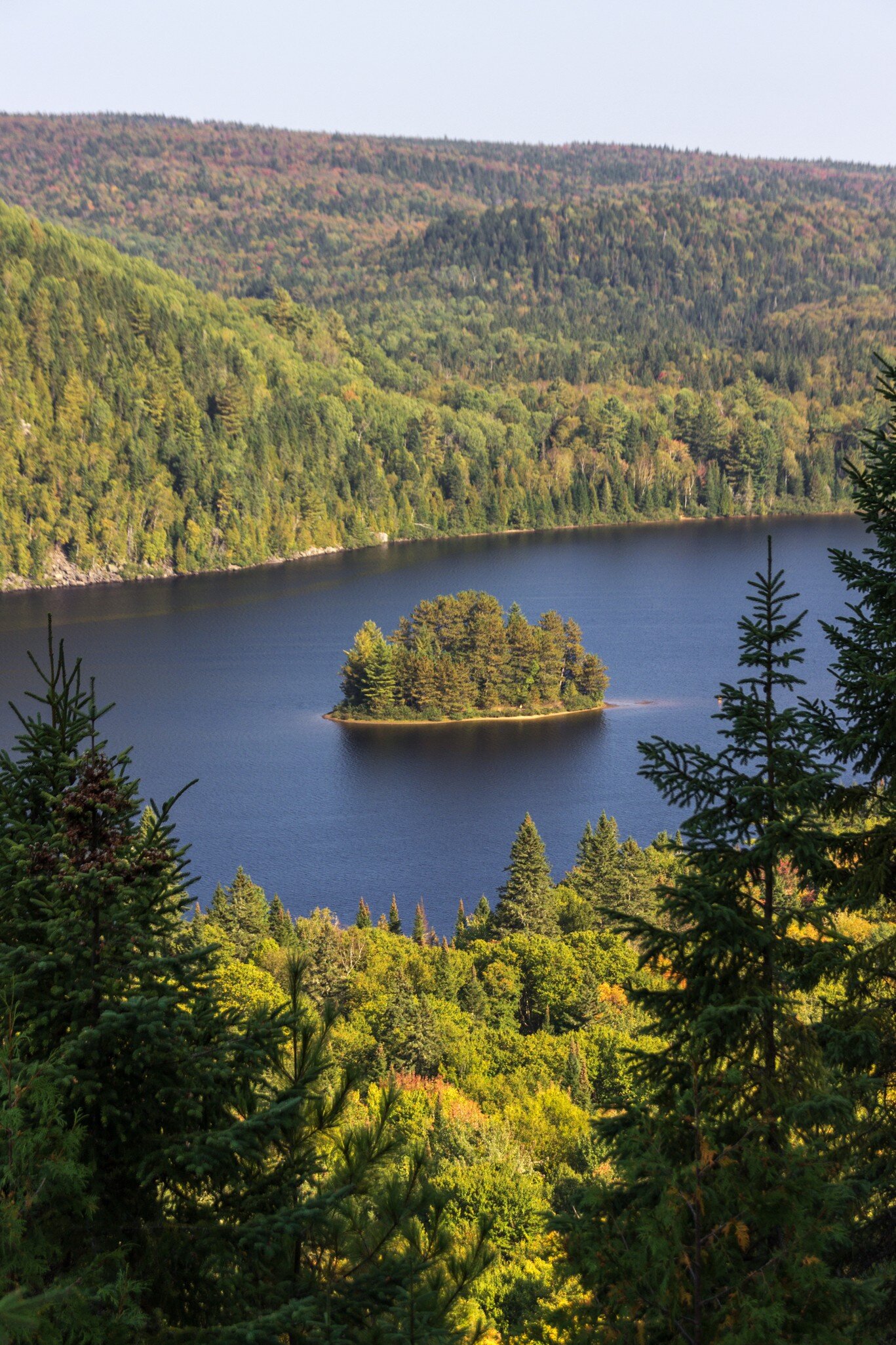 View of an island in the middle of a lake surrounded by greenery in La Mauricie National Park, Canada.