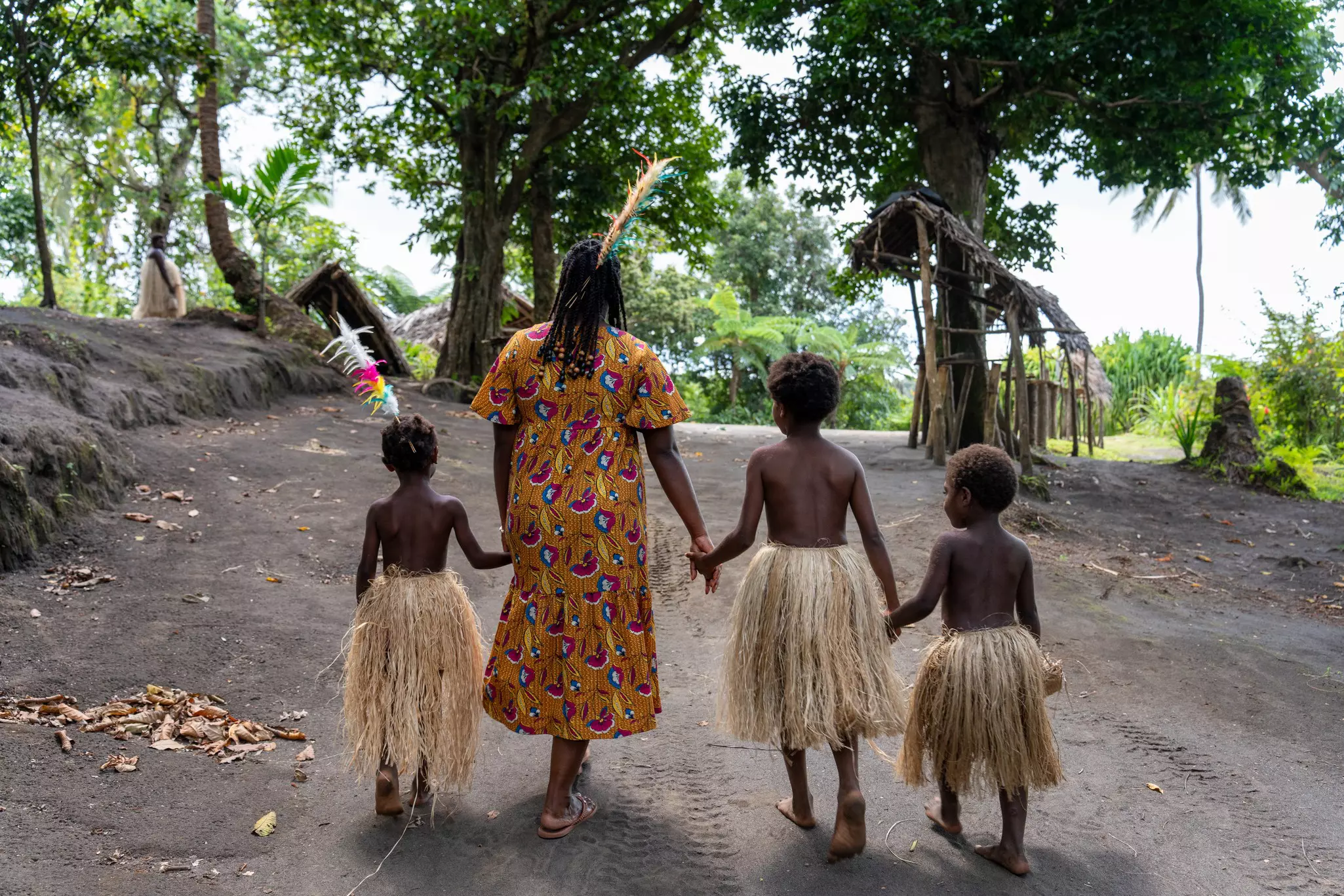 A woman walking with children with straw skirts