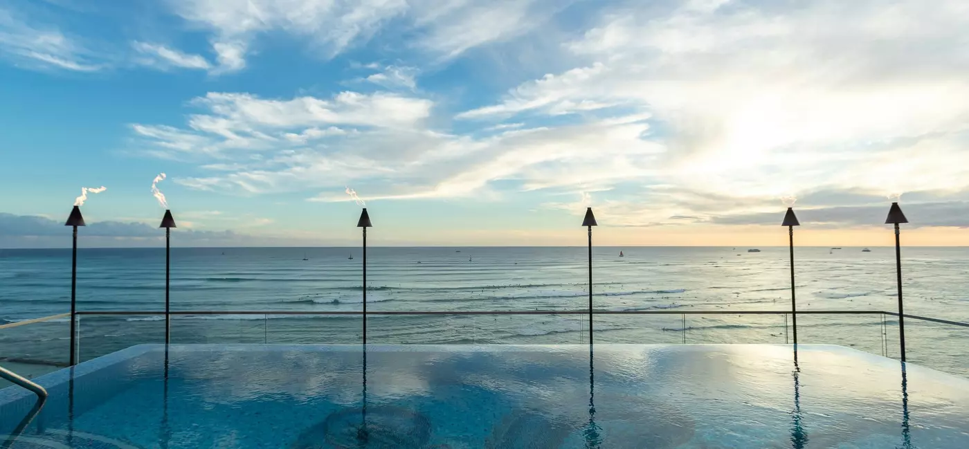 A swimming pool at the edge of the ocean at sunset.