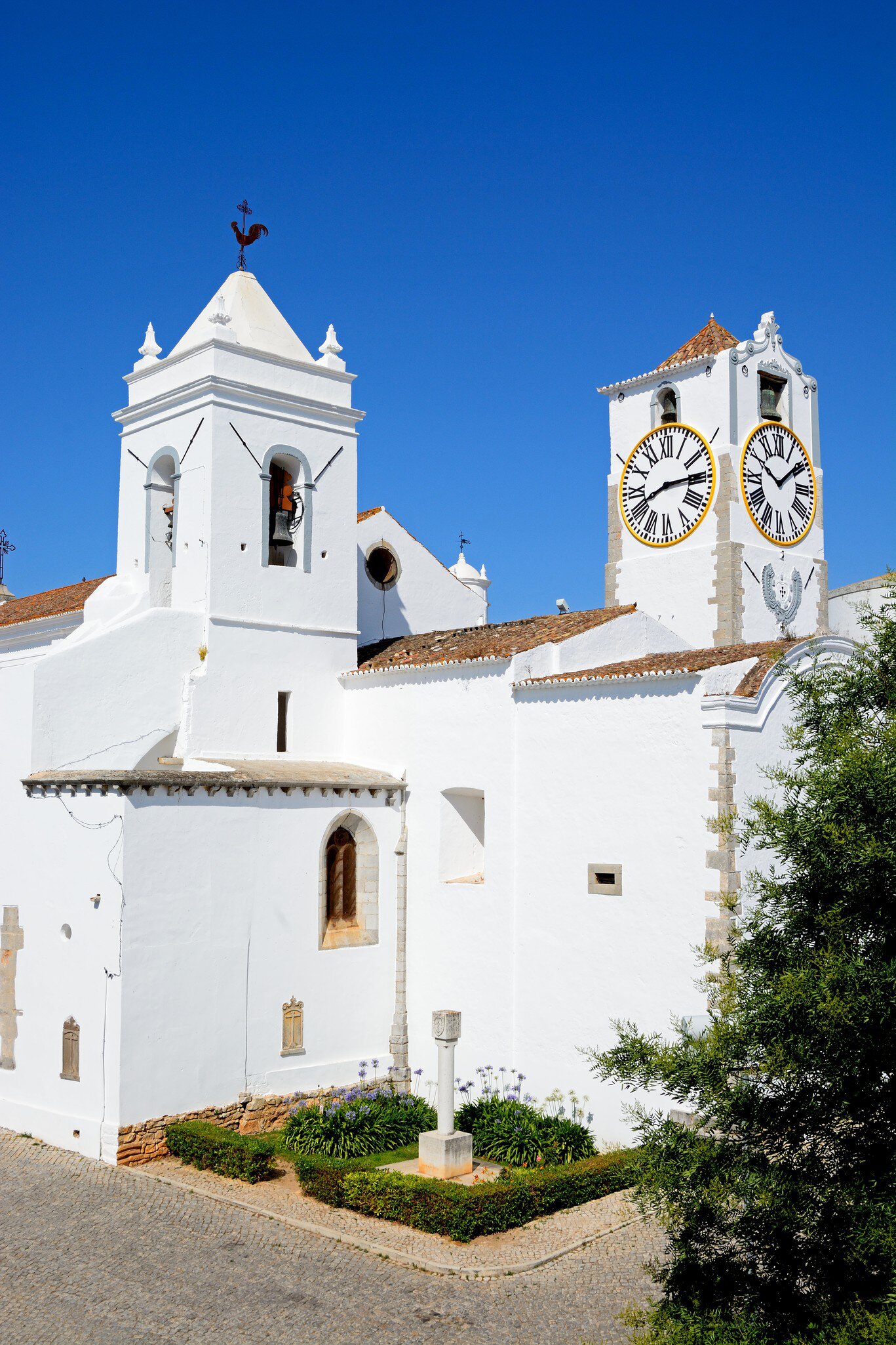Exterior view of the whitewashed Igreja de Santa Maria do Castelo in Tavira, Portugal.