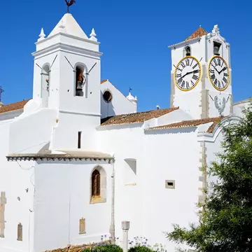 Exterior view of the whitewashed Igreja de Santa Maria do Castelo in Tavira, Portugal.