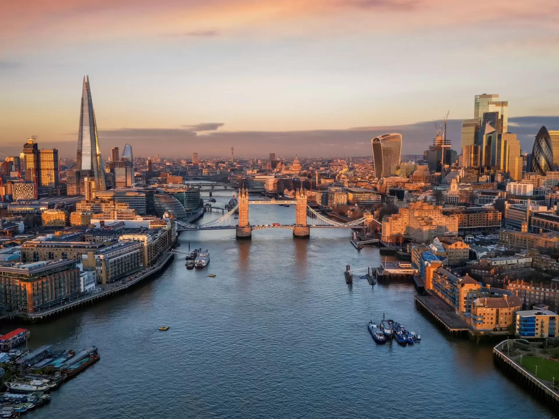 Panoramic view of the skyline of London during a sunrise with Tower Bridge and the skyscrapers of the City in golden, soft light