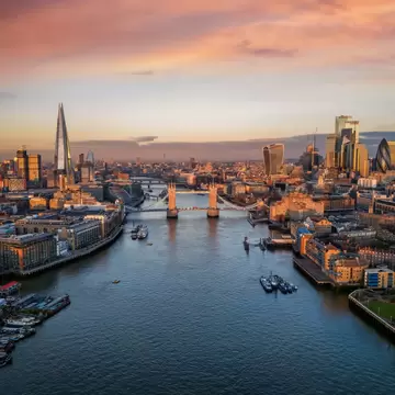 Panoramic view of the skyline of London during a sunrise with Tower Bridge and the skyscrapers of the City in golden, soft light